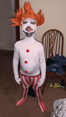 a child dressed in a clown costume with a red wig