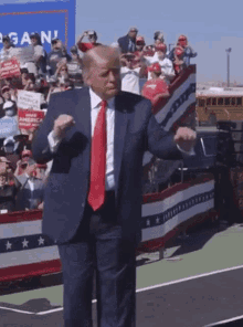 a man in a suit and tie is dancing in front of a crowd with a sign that says again