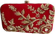 a red clutch bag with gold embroidery and sequins on a white background .