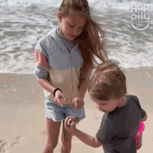 a boy and a girl are playing on the beach with the word hap pilu in the upper right corner