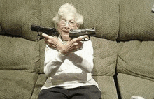 a woman is sitting on a couch holding two guns in her hands .