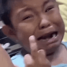 a young boy is crying and giving a middle finger .