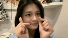 a girl is making a funny face with her fingers in front of her face