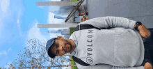 a man wearing a volcom sweatshirt stands in front of a city