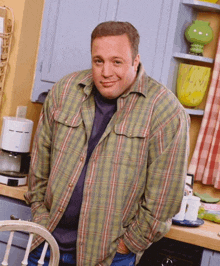 a man in a plaid shirt stands in front of a coffee maker