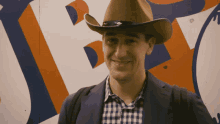 a man wearing a cowboy hat is smiling in front of a sign that says ' texas '