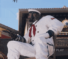 a man in a sailor 's uniform is kneeling down in front of a sign that says " state of play "