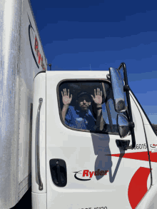 a man sitting in the driver 's seat of a white ryder truck