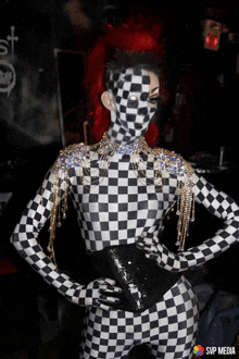 a woman in a black and white checkered bodysuit is standing with her hands on her hips in front of a svp media logo