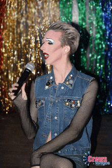 a woman in a denim jacket singing into a microphone with crews tango written on the bottom right