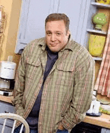 a man is standing in a kitchen with his hands in his pockets .