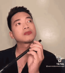 a man is applying lipstick to his lips with a pen .