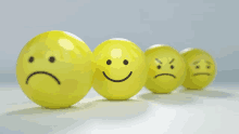 a row of yellow balls with smiley faces and sad faces