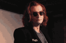 a man with long red hair wearing sunglasses and a suit says yup