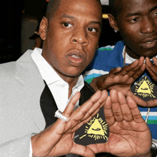 a man wearing a shirt with a triangle on it is standing next to another man