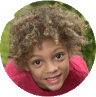 a young boy with curly hair is smiling in a pink shirt