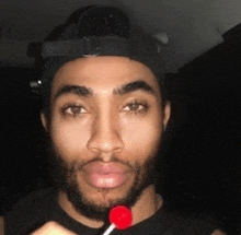 a man with a beard is eating a lollipop .