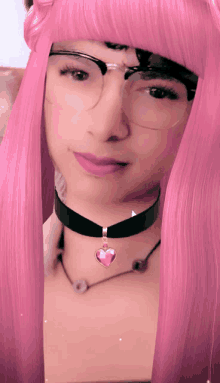 a woman with pink hair wearing glasses and a choker with a pink heart pendant