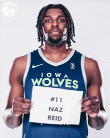 a man in a iowa wolves jersey holds a sign