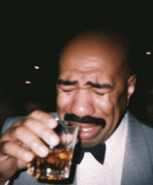 a bald man with a mustache is drinking from a glass