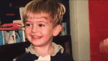 a young boy is smiling and holding a piece of paper in his mouth .