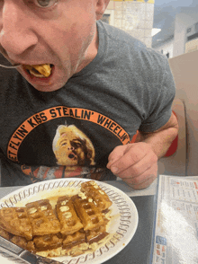 a man wearing a shirt that says flying kiss stealin ' wheeling is eating waffles