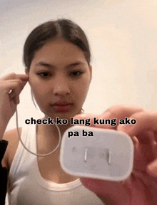 a woman in a white tank top is holding a charger in her hand with the caption check ko lang kung ako pa ba