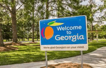 a welcome to georgia sign is sitting on the side of a road .