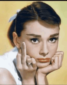 a woman is giving the middle finger with her hand on her face .