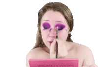 a woman is applying purple eyeshadow to her face .