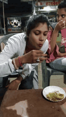 a woman sitting at a table with a plate of food and a sign that says ' a ' on it