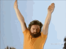 a man with a beard is doing a yoga pose with his arms outstretched .