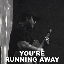 a black and white photo of a man playing a guitar with the words " you 're running away " below him