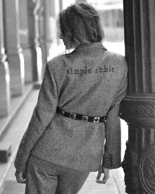 a woman wearing a jacket with simple chic embroidered on it