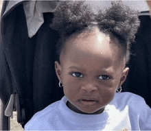 a little girl with a bun in her hair is sitting in a stroller .