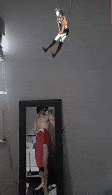 a man is taking a selfie in front of a mirror with a picture of a girl hanging from the ceiling