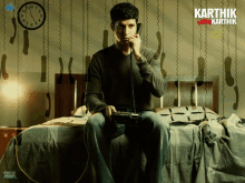 a man sitting on a bed talking on a phone with karthik written on the wall