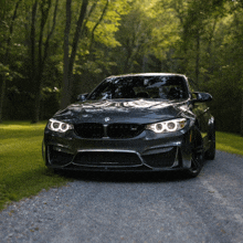 a bmw is parked on a dirt road in the woods