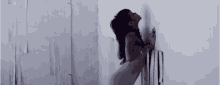 a naked woman is leaning against a wall in a room