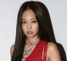 a close up of a woman wearing a red dress and a necklace with a chanel logo