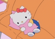 a hello kitty laying on a couch with a pink pillow