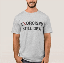 a man is wearing a grey t-shirt that says exorcised still deaf