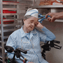 an elderly woman wearing a blue and white striped shirt is sitting in a wheelchair while a man holds a horn