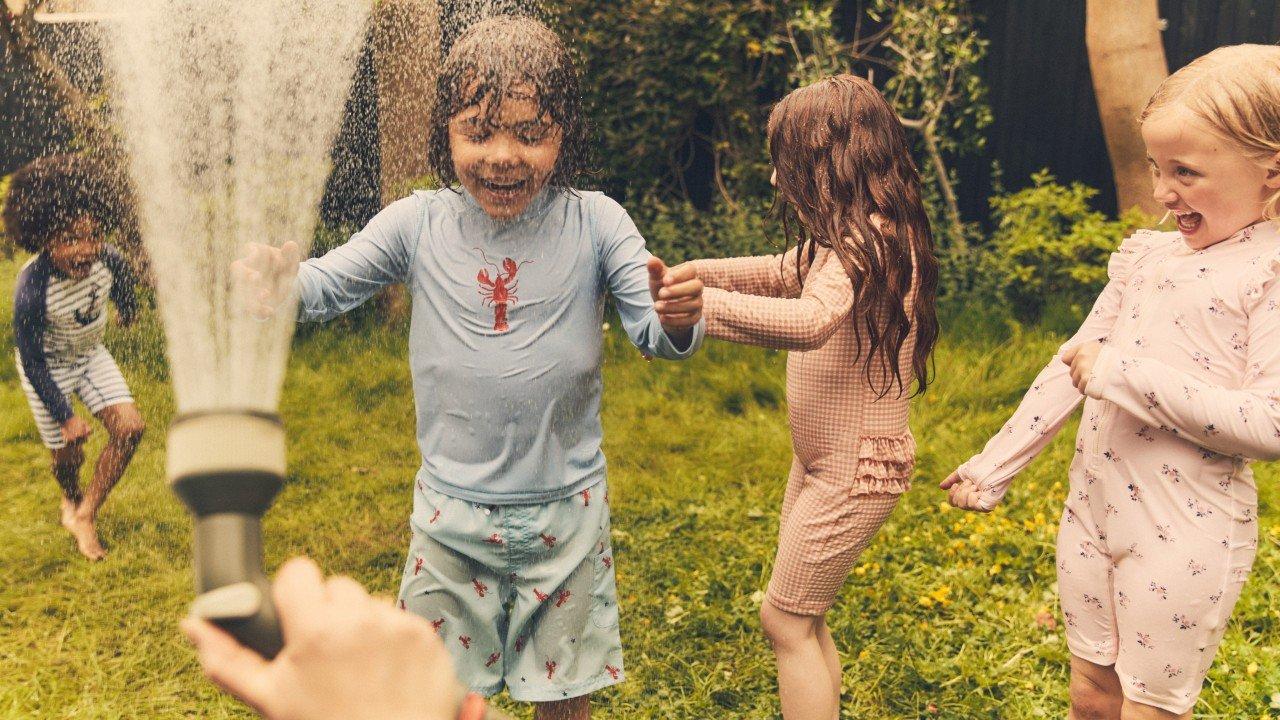 a group of children playing in a yard with a hose