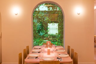 Mesa junto a una ventana con vegetación al otro lado en el restaurante Mudr Plant Based Madrid