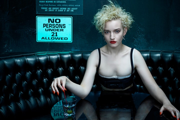 Julia Garner seated in a bar booth wearing a bra top by Miu Miu.