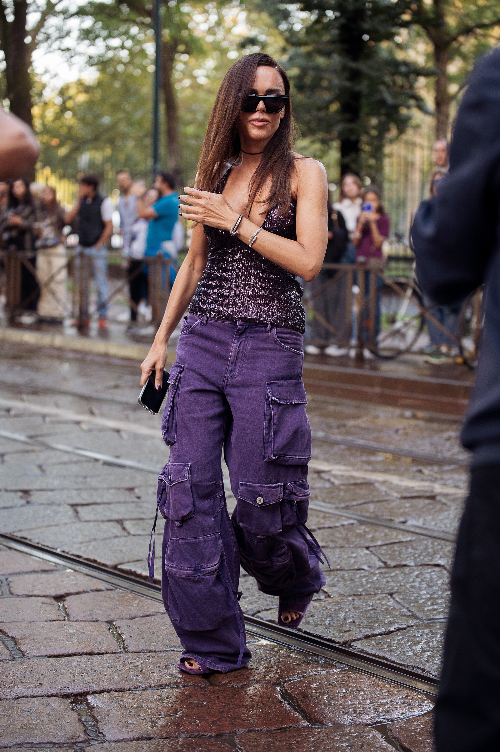 Mujer luce unos jeans cargo con blusa de lentejuelas y sandalias en el street style