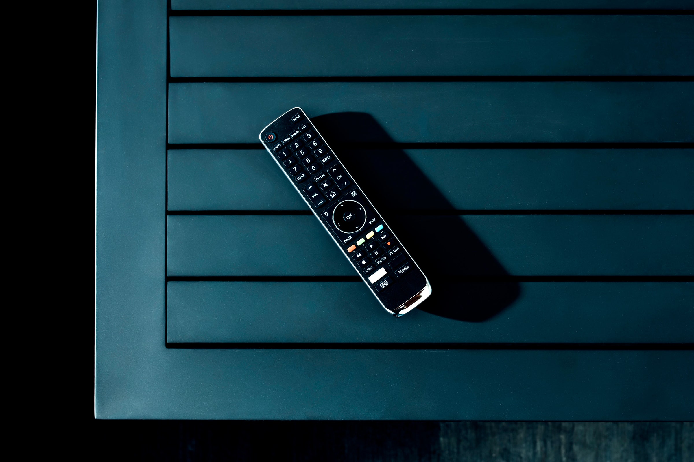 Television remote on a table in dramatic lighting