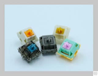 A collection of 5 small square components for a mechanical keyboard