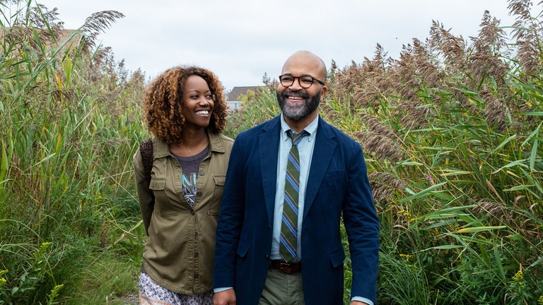 A still image from the movie American Fiction where Thelonious  and Coraline  are walking through tall grass while smiling.